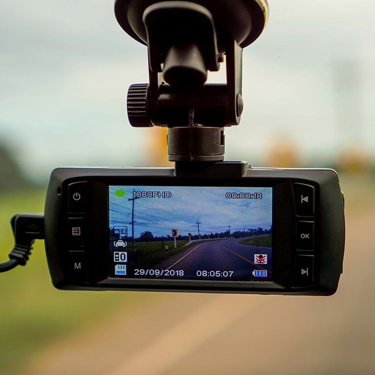 Close-up of a dashboard camera displaying a road view, highlighting the use of in-vehicle technology for monitoring and improving fleet safety.
