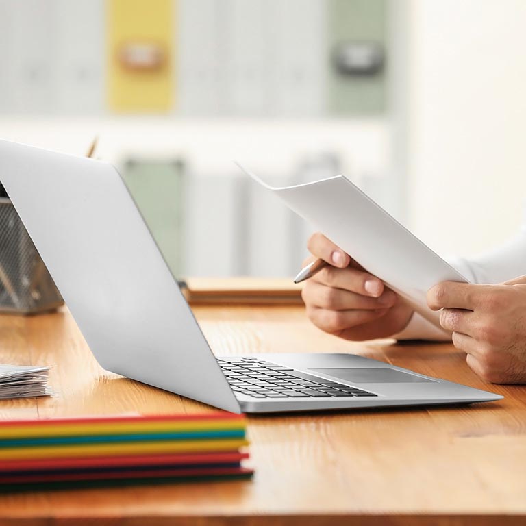 man holding papers and laptop