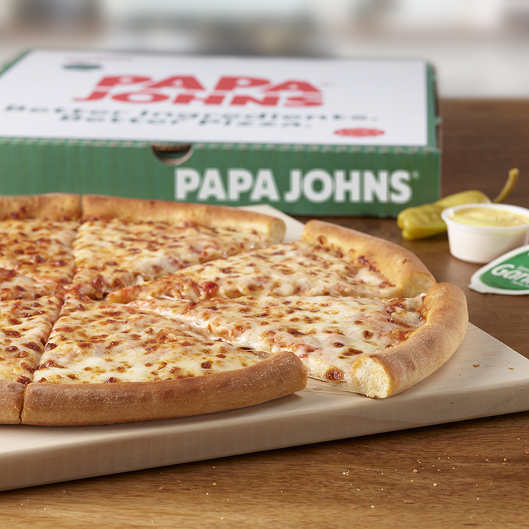 Papa Johns orinigal crust cheese pizza on table, next to an pickled pepperoncini, garlic dip and Papa Johns pizza box